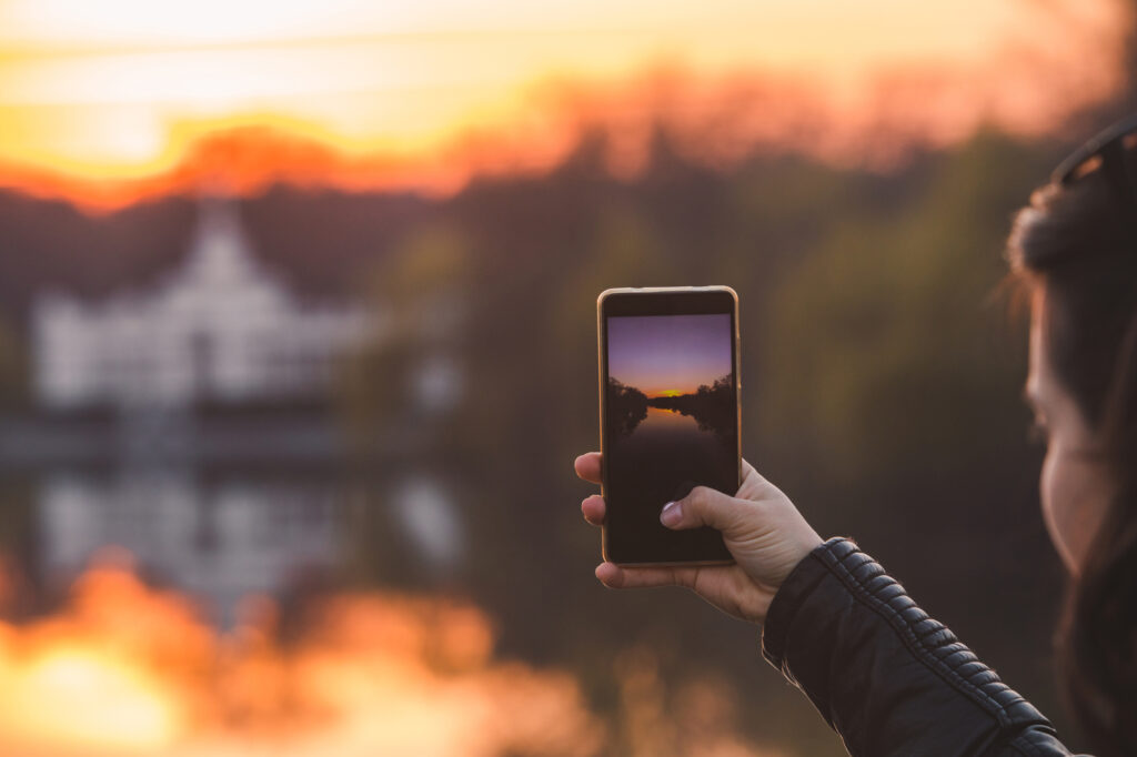 woman taking picture of sunset on her phone. lifestyle concept