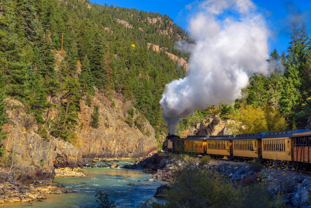 Historic steam engine train travels from Durango to Silverton through the San Juan Mountains along the Animas River in Colorado, USA.