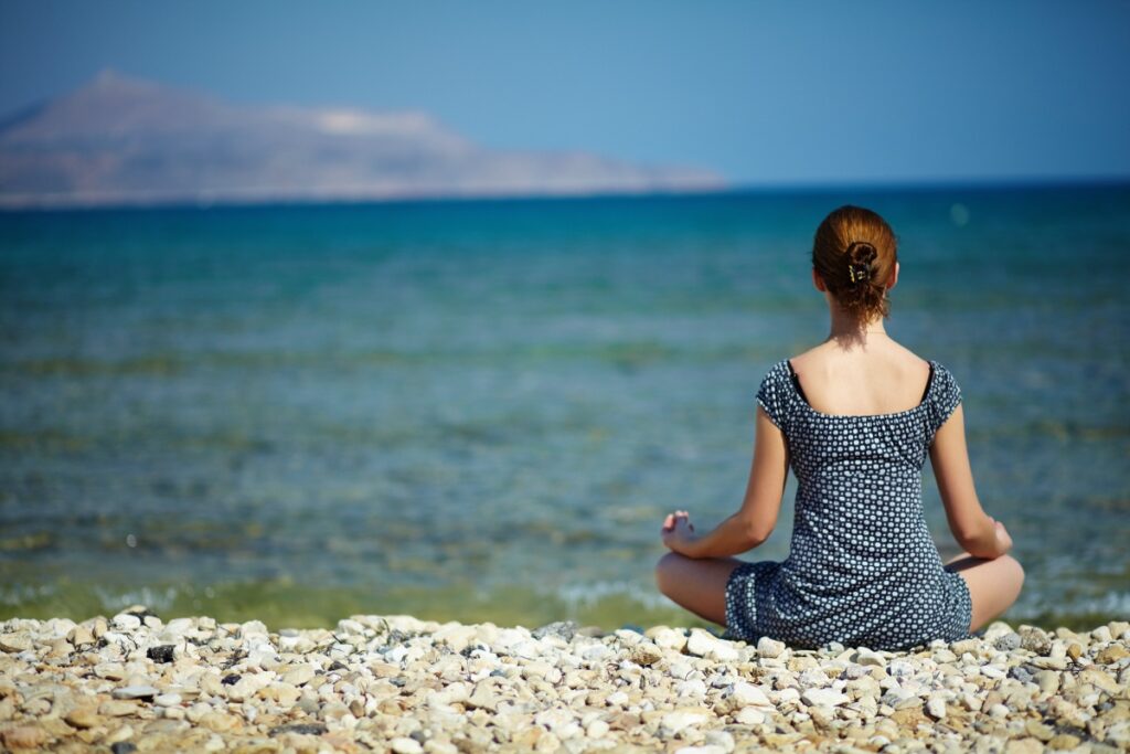 Young woman sitting on the beach enjoying peaceful moment