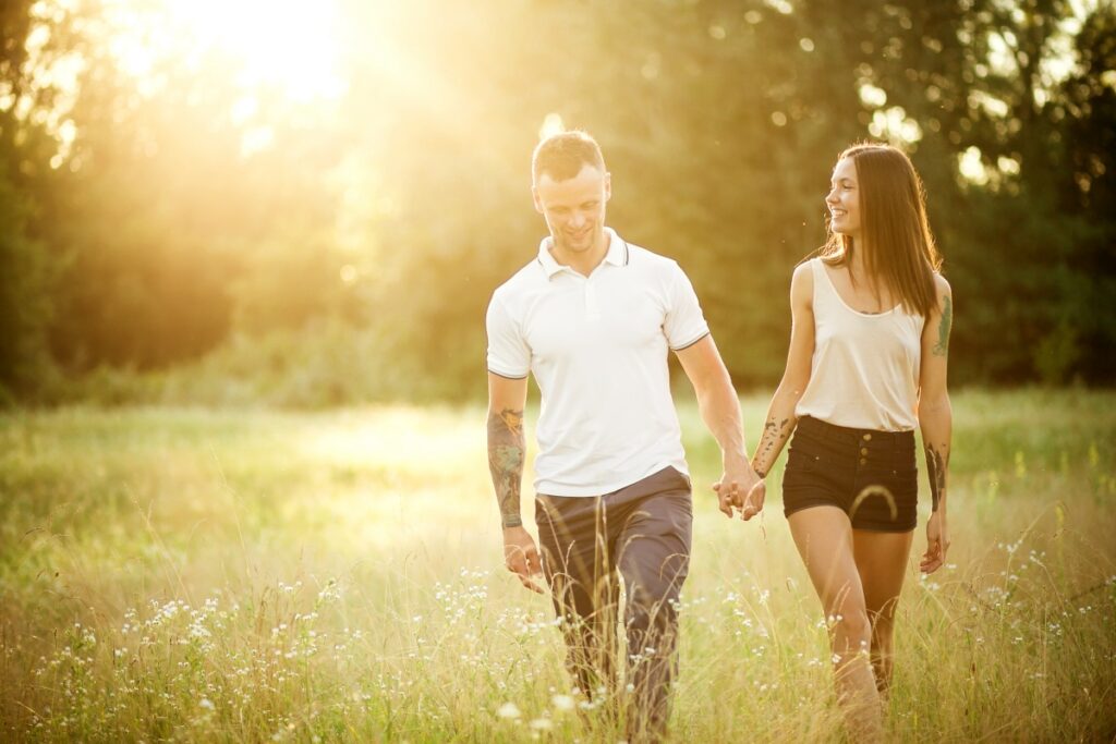 A man and a girl with a tattoo on the nature holding hands