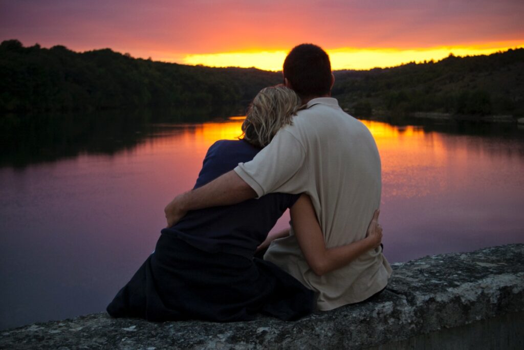 A couple gently embrace as the sun sets