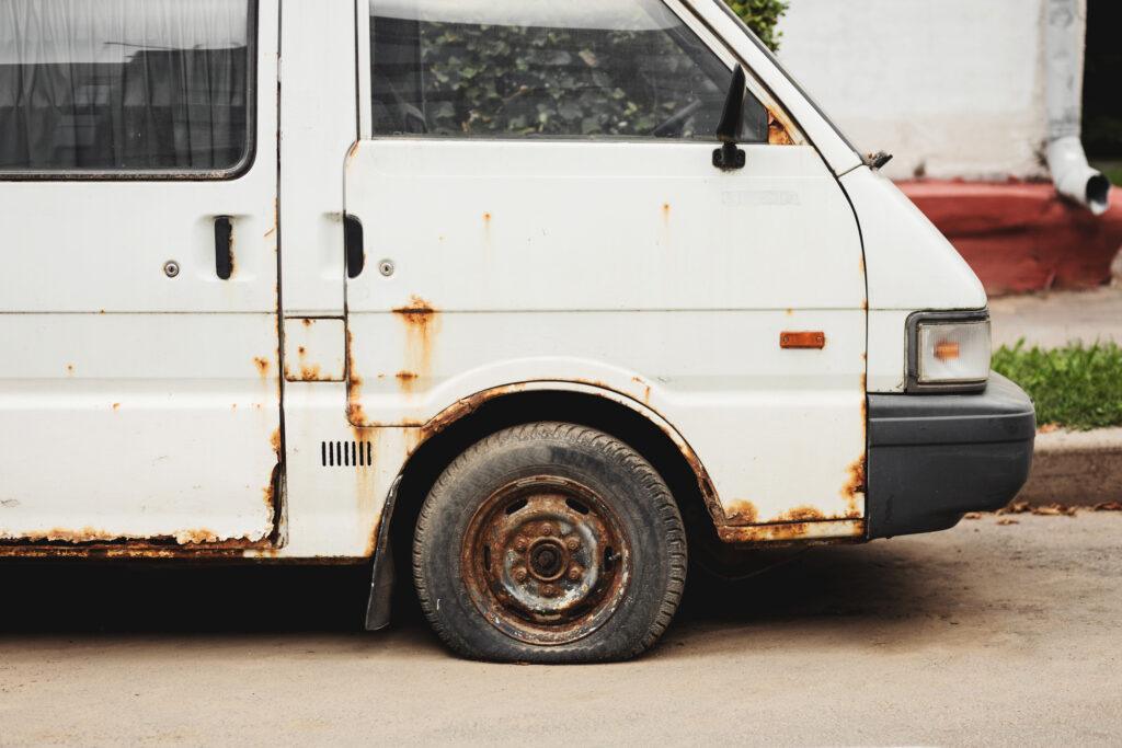 White rusty abandoned compact van. Unnecessary malfunctioning car junk truck abandoned on the side of the road