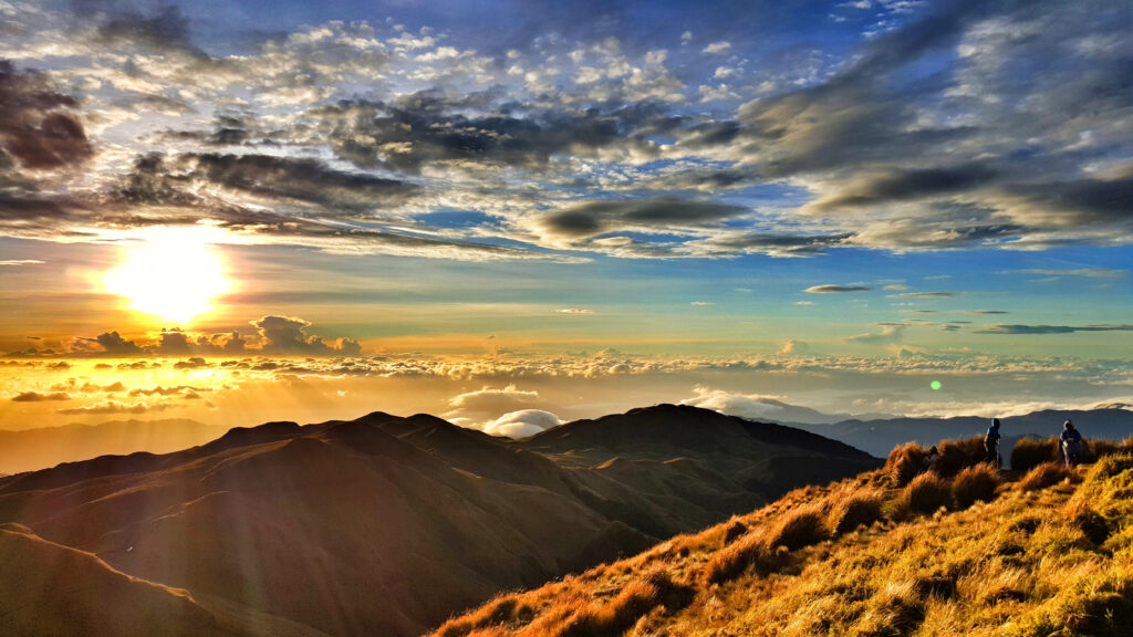 A stunning view of bright sunset sun in a cloudy sky over the mountains