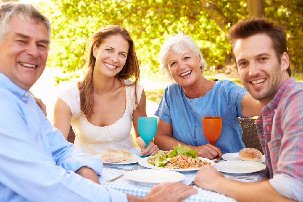 A senior and a young adult couple eating together outdoors