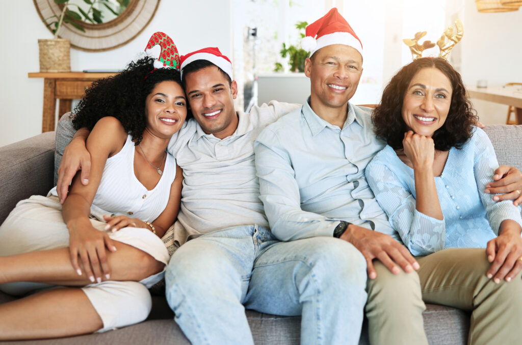 Christmas, happy family and people on holiday in a home celebrating on vacation and bonding in a house. Portrait, men and women on a couch or sofa in December for celebration together in living room.