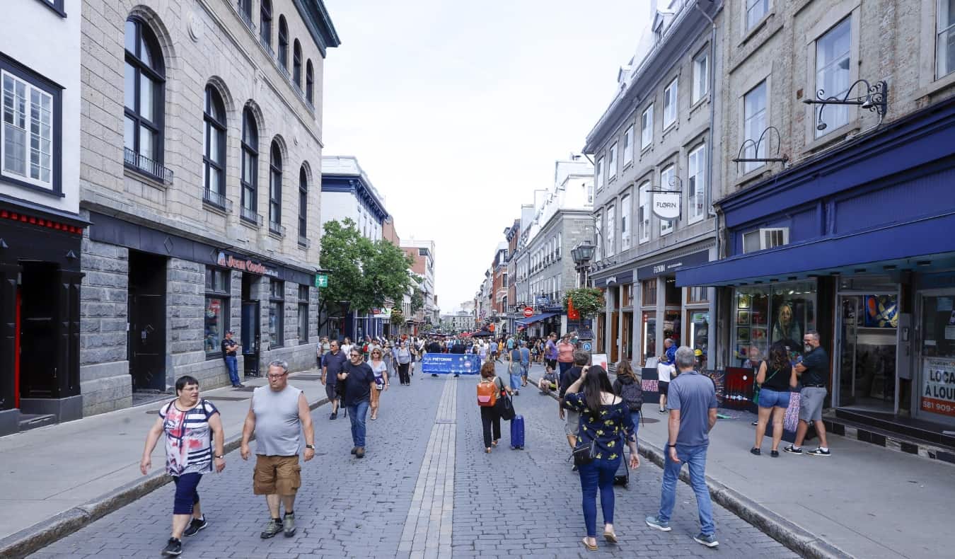 People walking down the middle of the cobblestoned rue Saint-Jean in the summer when it's closed to pedestrians