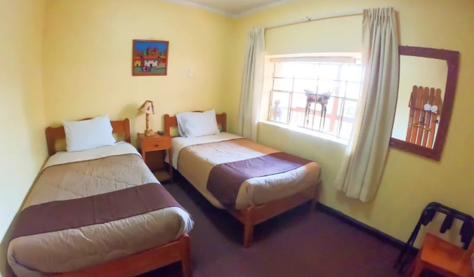 Twin Beds in a simple yellow room at Hospedaje Turístico Recoleta, a hostel in Cusco, Peru