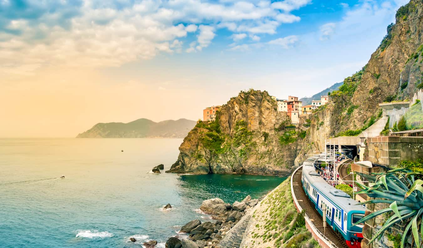 A train traveling along the rugged cliffside villages of Italy at sunset