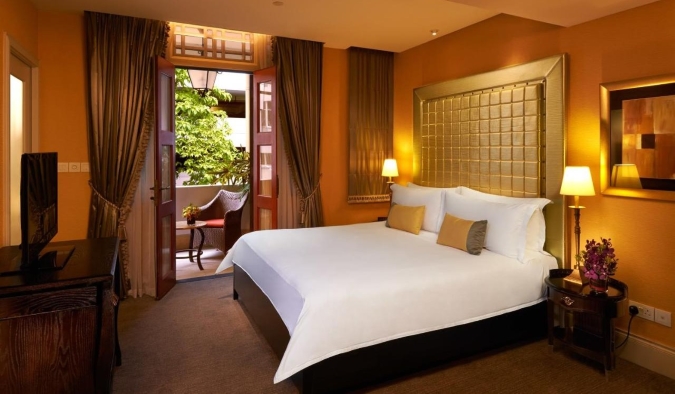 A boldly decorated hotel room with orange walls and a large gold headboard at The Scarlet hotel in Singapore